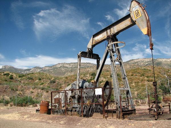 An oil well with the mountains of the Sespe Condor Sanctuary in the background.